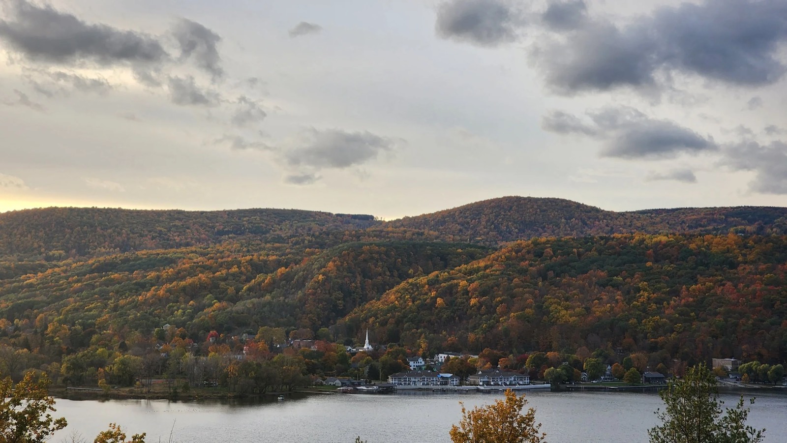 Hammondsport and the south end of Keuka Lake in October, with fall color on the wooded hills, a white church steeple and the village waterfront