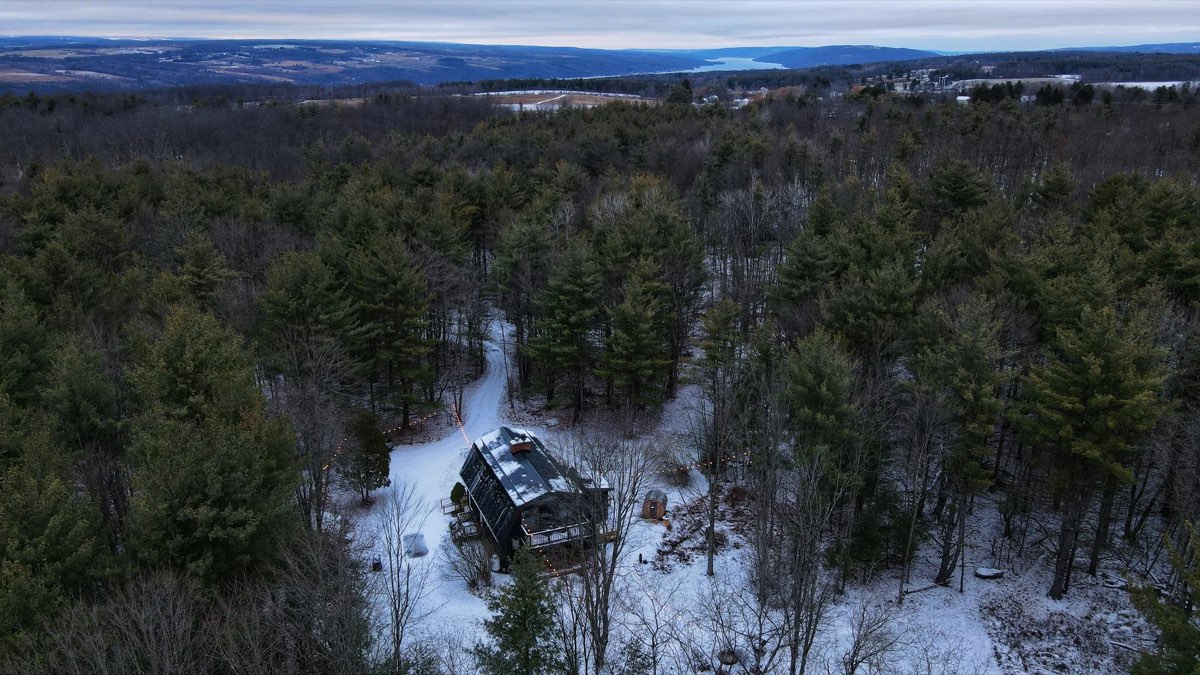 Winter aerial view of the snow-covered cabin with Keuka Lake in the distance